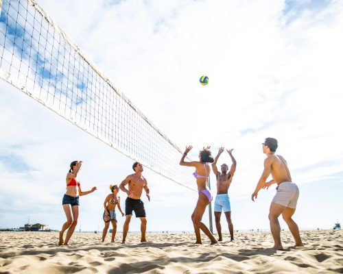 Group of friends playing beach volley - Multi-ethic group of people having fun on the beach