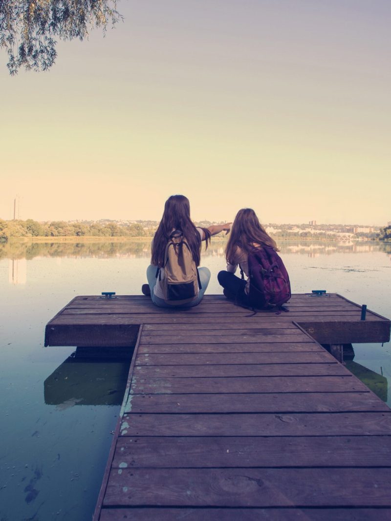 girls sitting on doc on Lake